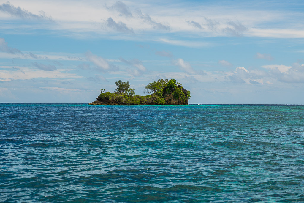 Small rocky wooded islet alone on a deep blue sea, Misool, Raja Ampat, Indonesia