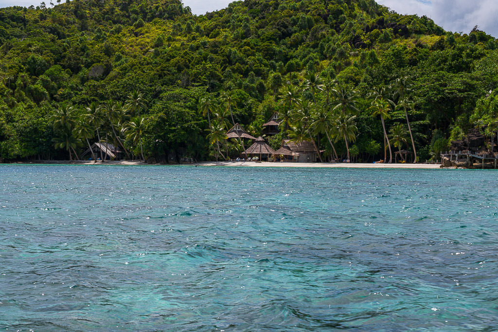 Vue large de villas de plage sous une colline couverte de jungle, Misool, Raja Ampat, Indonésie