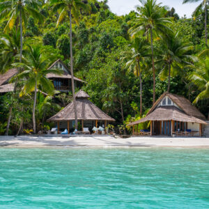 Vue rapprochée de villas en chaume entre cocotiers et eau turquoise, Misool, Raja Ampat, Indonésie