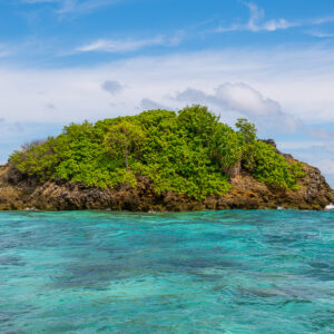 Small green-capped rocky islet over turquoise reef, Misool, Raja Ampat, Indonesia