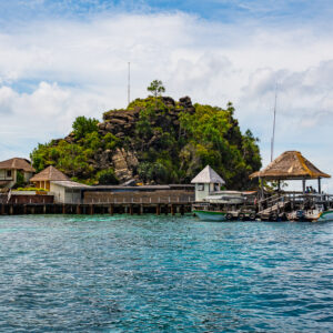 Resort jetty with buildings, gazebo and boats before a rocky island, Misool, Raja Ampat, Indonesia