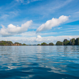 Line of karst islets on the horizon above glassy water, Misool, Raja Ampat, Indonesia