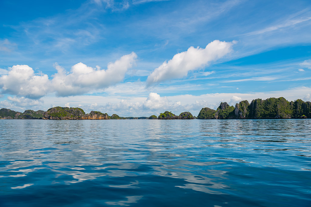 Line of karst islets on the horizon above glassy water, Misool, Raja Ampat, Indonesia
