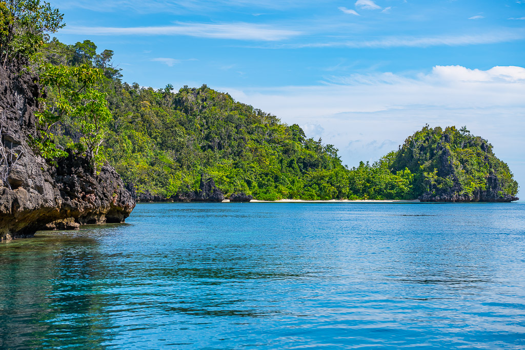 Jungle-covered islands with a hidden white beach between cliffs, Misool, Raja Ampat, Indonesia