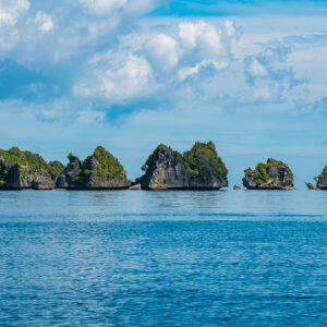 Five small karst islets in a line on a calm sea, Misool, Raja Ampat, Indonesia
