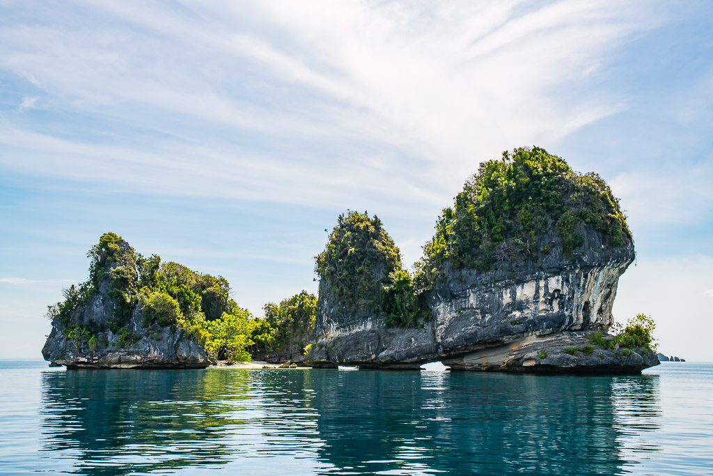 Undercut mushroom karst islets reflected in still water, Misool, Raja Ampat, Indonesia