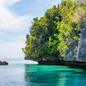 Undercut limestone island over emerald water with small rock, Misool, Raja Ampat, Indonesia