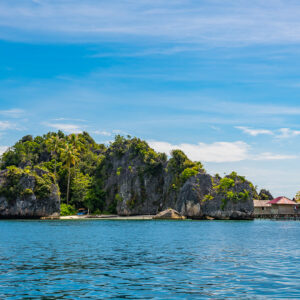 Karst island with a small red-roofed building at its tip, Misool, Raja Ampat, Indonesia