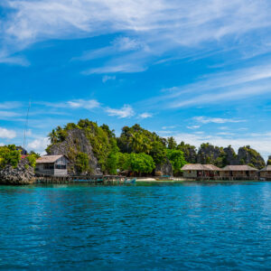 Low karst islands with a row of stilt huts, wide view, Misool, Raja Ampat, Indonesia