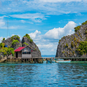 Cabane sur pilotis à toit rouge sur un ponton entre des îlots karstiques, Misool, Raja Ampat, Indonésie