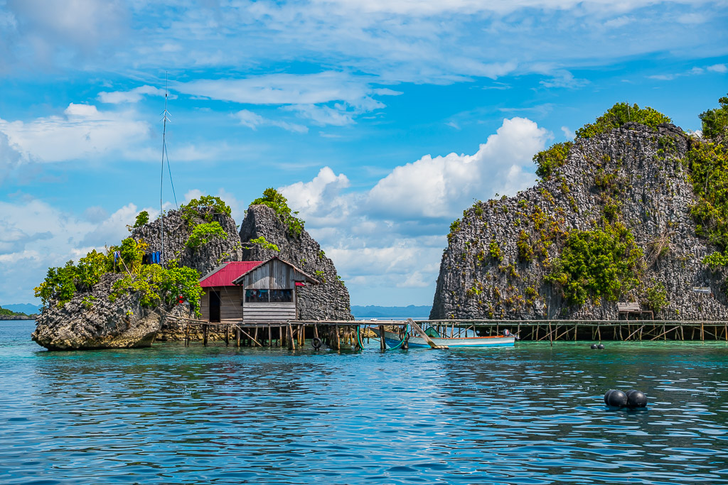 Cabane sur pilotis à toit rouge sur un ponton entre des îlots karstiques, Misool, Raja Ampat, Indonésie