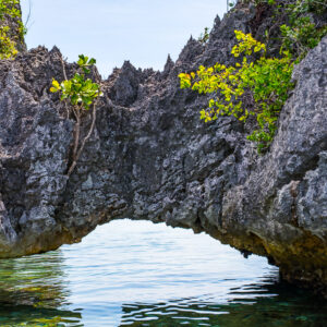 Arche calcaire naturelle au-dessus d’une eau calme encadrant le ciel, Misool, Raja Ampat, Indonésie