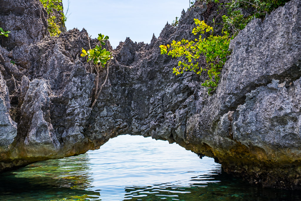 Arche calcaire naturelle au-dessus d’une eau calme encadrant le ciel, Misool, Raja Ampat, Indonésie