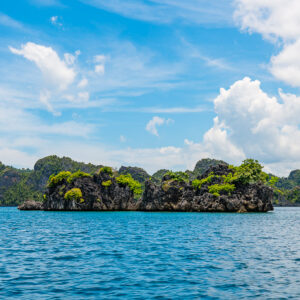 Low line of karst islets under bright cumulus clouds, Misool, Raja Ampat, Indonesia