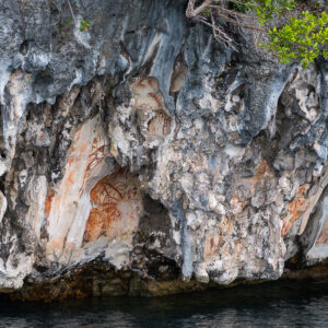 Red ochre rock paintings on a limestone cliff above the water, Misool, Raja Ampat, Indonesia