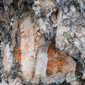 Panel of red ochre rock paintings in a limestone overhang, vertical, Misool, Raja Ampat, Indonesia