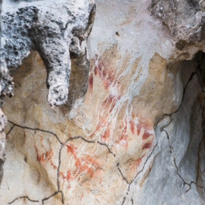 Faded red ochre hand stencils on a cracked limestone wall, Misool, Raja Ampat, Indonesia