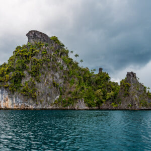 Steep karst island with sheer white cliff under a stormy sky, Misool, Raja Ampat, Indonesia