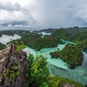 Karst islands and turquoise lagoons beyond a foreground rock pinnacle, Misool, Raja Ampat, Indonesia