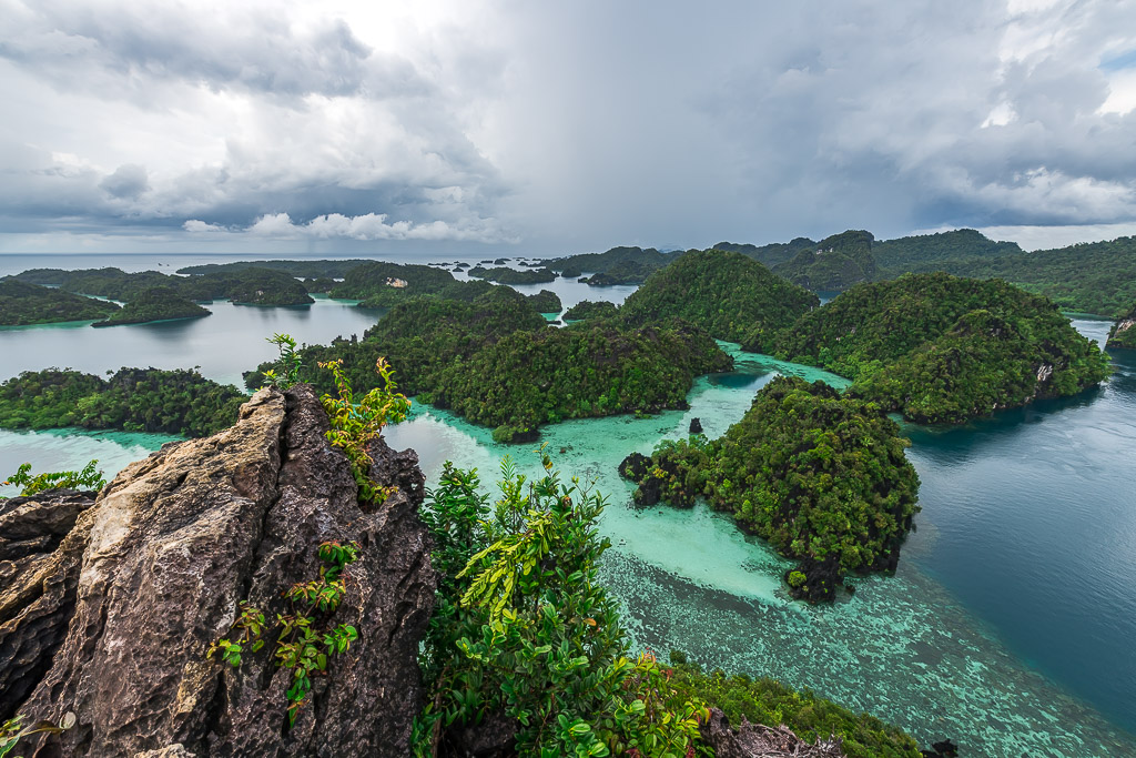 Karst islands and turquoise lagoons beyond a foreground rock pinnacle, Misool, Raja Ampat, Indonesia