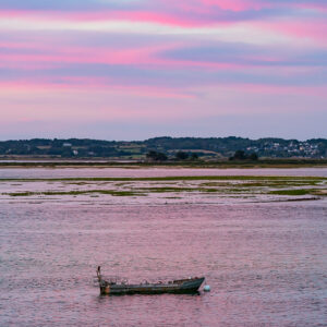 Small boat on pink water under pastel pink sunset clouds, Le Croisic, Brittany, France