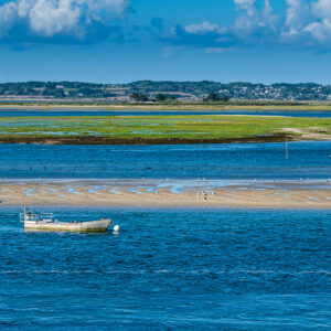 Small flat work boat moored in blue channel before green salt meadow, Le Croisic, Brittany, France