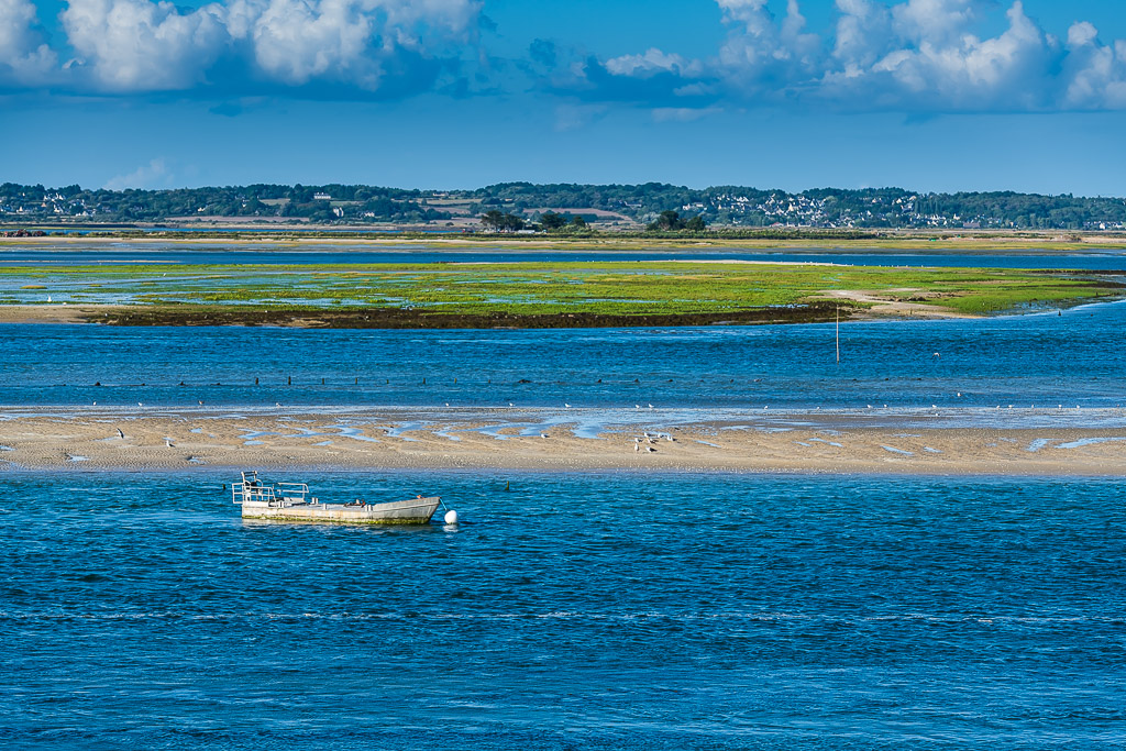 Small flat work boat moored in blue channel before green salt meadow, Le Croisic, Brittany, France
