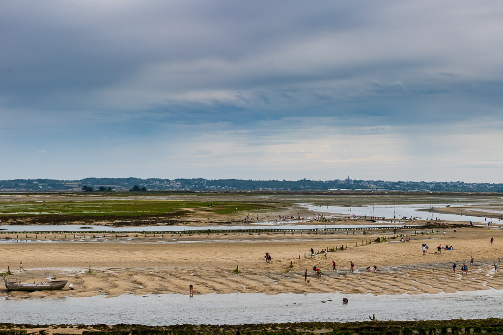 Vue large des bancs de sable bondés de pêcheurs à pied sous un ciel gris nuageux, Le Croisic, Bretagne, France