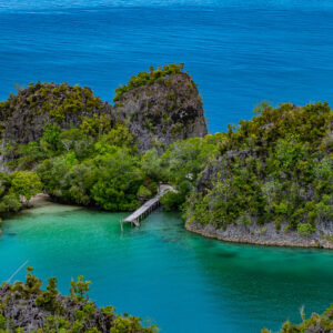 Small jetty and beach nestled between karst islets, Waigeo, Raja Ampat, Indonesia