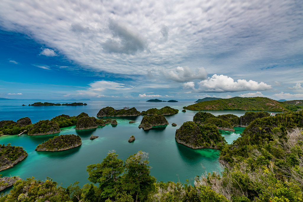 Sweeping view of turquoise lagoon and karst islets under clouds, Waigeo, Raja Ampat, Indonesia