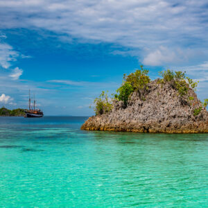Rocky islet in crystal-clear turquoise water, closer framing, Raja Ampat, Indonesia