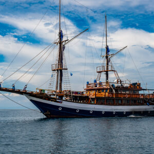 Two-masted phinisi liveaboard sailing near a small island, Raja Ampat, Indonesia