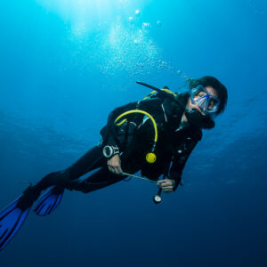 Woman diver smiling into the camera in blue water, close framing, Raja Ampat, Indonesia