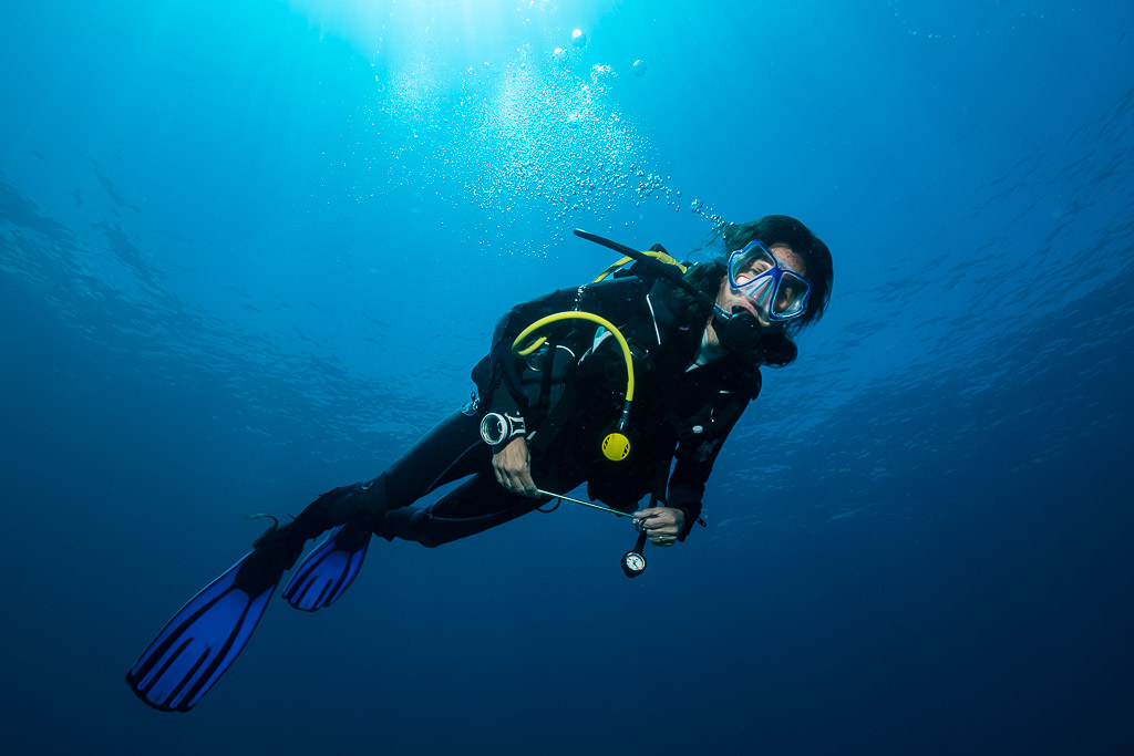 Woman diver smiling into the camera in blue water, close framing, Raja Ampat, Indonesia