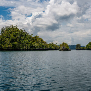 Hilly forested island with small islets under dramatic clouds, Waigeo, Raja Ampat, Indonesia
