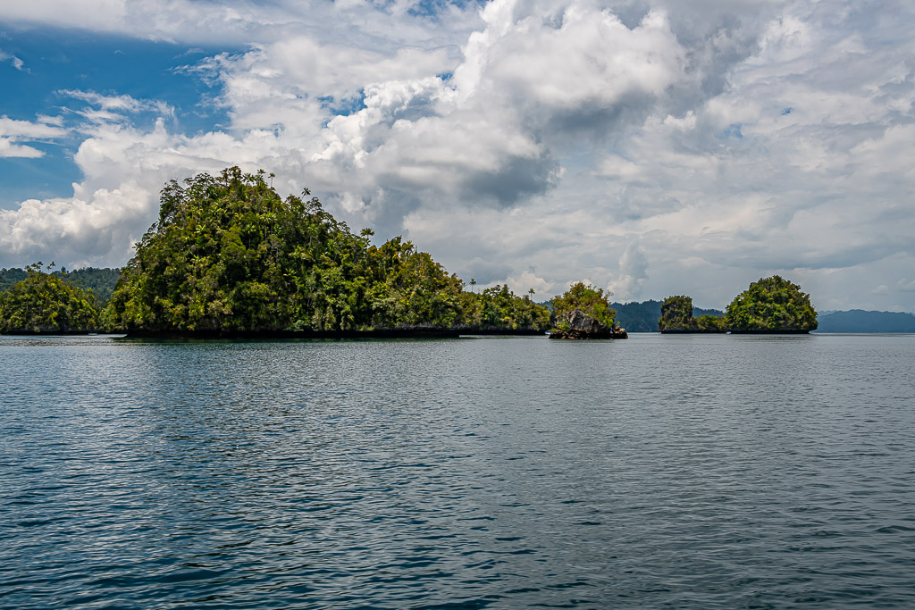 Hilly forested island with small islets under dramatic clouds, Waigeo, Raja Ampat, Indonesia