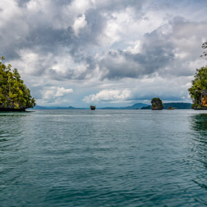 Two forested islets framing a distant pinnacle and horizon, Waigeo, Raja Ampat, Indonesia