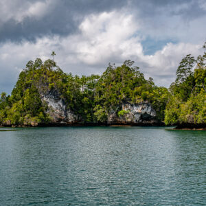 Limestone islets covered in jungle under cloudy sky over calm lagoon, Waigeo, Raja Ampat, Indonesia