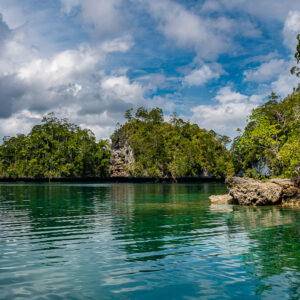 Channel between karst islets with rocky outcrop under blue sky, Waigeo, Raja Ampat, Indonesia