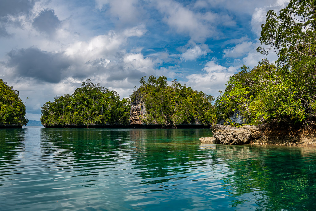 Channel between karst islets with rocky outcrop under blue sky, Waigeo, Raja Ampat, Indonesia