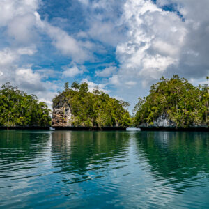 Three jungle islets reflected in calm lagoon under dramatic clouds, Waigeo, Raja Ampat, Indonesia