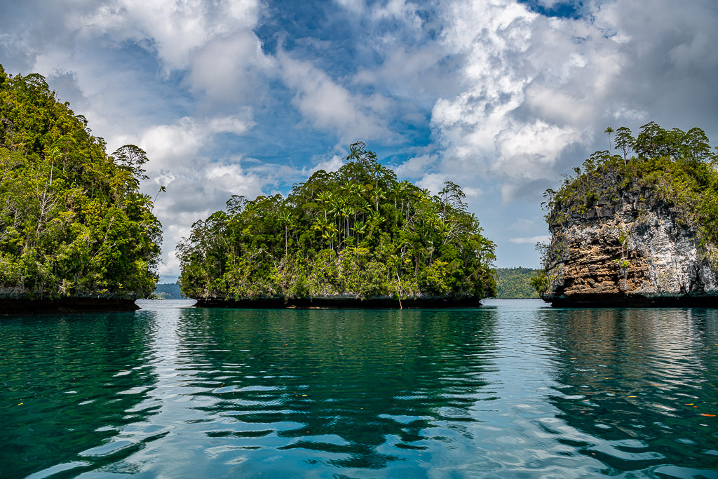 Islet framed by two limestone cliffs with reflections in turquoise water, Waigeo, Raja Ampat, Indonesia