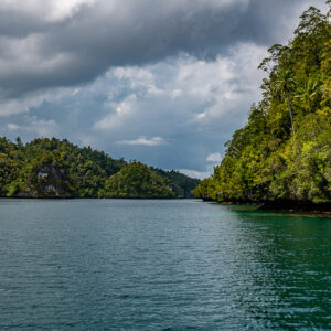 Forested headland on the right and distant hills across a calm bay, Waigeo, Raja Ampat, Indonesia