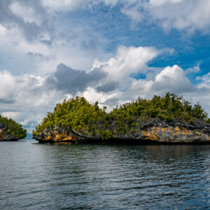 Two islets of different sizes with orange eroded bases under clouds, Waigeo, Raja Ampat, Indonesia