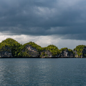 Alignement d’îlots karstiques sous un ciel sombre et orageux, Waigeo, Raja Ampat, Indonésie