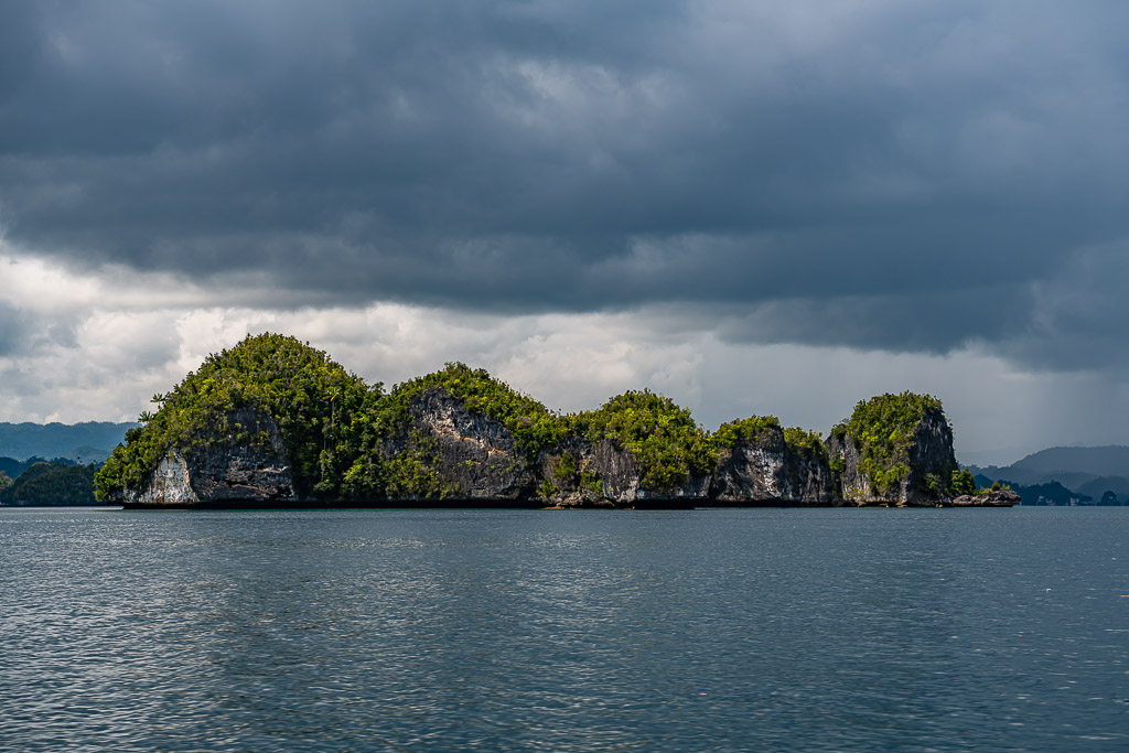 Alignement d’îlots karstiques sous un ciel sombre et orageux, Waigeo, Raja Ampat, Indonésie