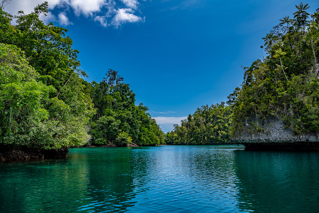 Emerald channel between forested islets with clouds, wider view, Waigeo, Raja Ampat, Indonesia