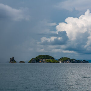 Rain squall over distant islets and rock pinnacle with towering cumulus, Waigeo, Raja Ampat, Indonesia