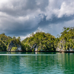Alignement de falaises karstiques creusées sous de spectaculaires nuages gris, Waigeo, Raja Ampat, Indonésie