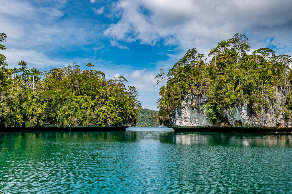 Gap between two jungle islets with white cliffs and reflections, Waigeo, Raja Ampat, Indonesia